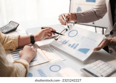 Team of two asian male and female business people working together discussing new financial graph data on office table with laptop and digital tablet. - Shutterstock ID 2321242227