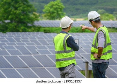 A Team Of Two Engineers Are Working To Install Solar Panels At A Solar Power Station. Engineer Team Discussing The Work To Install Solar Cells