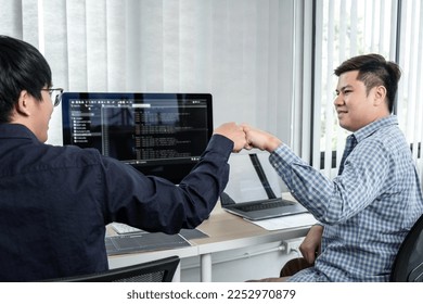 Team of two professional programmers working on website projects in software development and making a fist-bump after mission complete making coding and typing data code password security in office