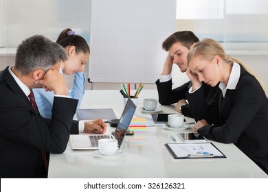 Team Of Unhappy Businesspeople Sitting In Business Meeting