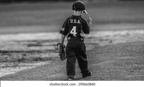 Team USA
Picture Of A Young Boy Walking Away From The Camera. He's Wearing  A Baseball Uniform With U.S.A. On The Back And An American Flag On His Sleeve. He's Holding 1 Finger In The Air.