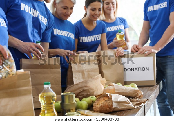 Team of volunteers collecting food donations at\
table, closeup