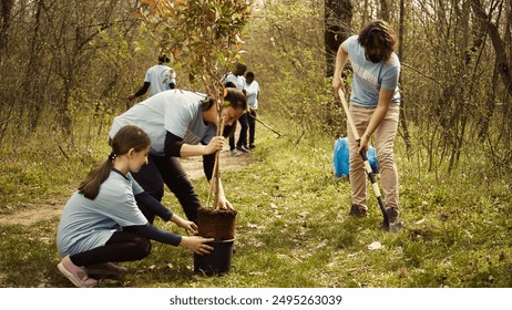 Team of volunteers growing the natural habitat in a forest, planting trees and preserving nature by taking action and fighting to save the planet. Activists doing community service. Camera B. - Powered by Shutterstock