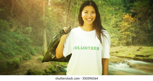 Team Of Volunteers Picking Up Litter In Park Against Rapids Flowing Along Lush Forest