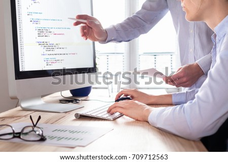 Team of web app developers coding website source code and debugging on computer screen before deployment