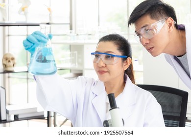 Team Work Asian Woman And Man Scientists Analyzing Study Data And Evaluating Microscope Success For Work Shop. Health Care Researchers Doing Some Research With Dropper Chemical Testing In Life Science