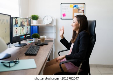 Team Work Meeting. Happy Young Woman Wearing Pajamas And A Blazer Waving To Her Co-workers During An Online Video Call From Home