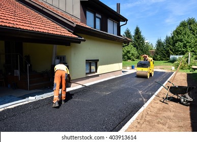 Team of Workers making and constructing asphalt road construction with steamroller. The top layer of asphalt road on a private residence house driveway - Shutterstock ID 403913614