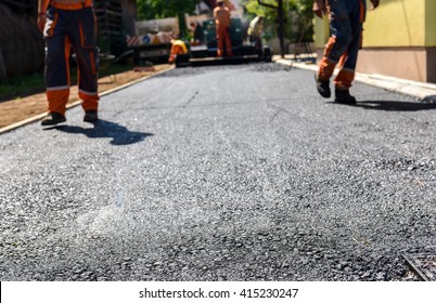 Team Of Workers Making And Constructing Asphalt Road Construction With Finisher. The Top Layer Of Asphalt Road On A Private Residence House Driveway