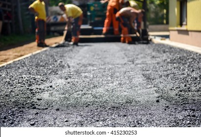 Team Of Workers Making And Constructing Asphalt Road Construction With Finisher. The Top Layer Of Asphalt Road On A Private Residence House Driveway