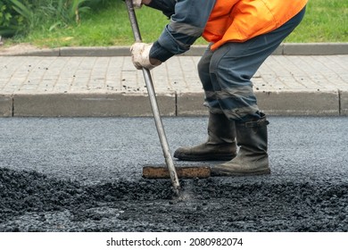 A team of workers on the road during the laying of new asphalt. At the construction site, asphalt laying equipment and workers with shovels and in special clothes. Road surface repair - Shutterstock ID 2080982074