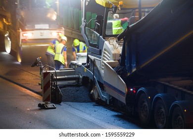 Team Of Workers Repairing Street Asphalt At Night Time With Heavy Machinery