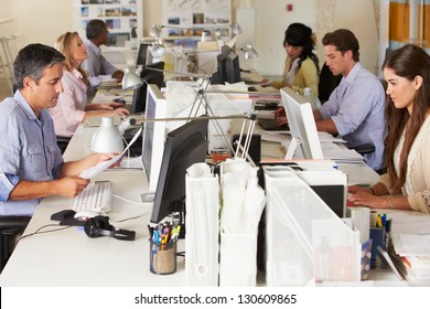 Team Working At Desks In Busy Office