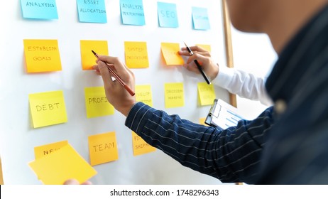 Team working in office putting sticky note on white board analyzing strategy of business. - Shutterstock ID 1748296343