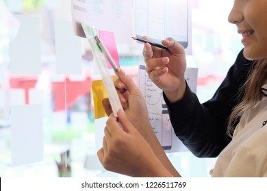 Team working with software development creative and using note paper on glass wall.