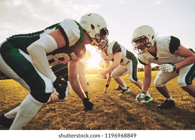 Team of young American football players lining up in formation during an afternoon practice session - Powered by Shutterstock