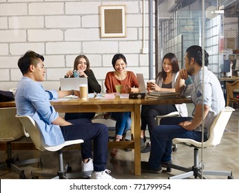 Team Of Young Asian And Caucasian Entrepreneurs Having A Pleasant Conversation In Meeting Room.