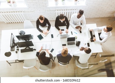 A Team Of Young Businessmen Sitting At The Table, Top View, Working And Communicating Together In An Office. Corporate Businessteam And Manager In A Meeting.