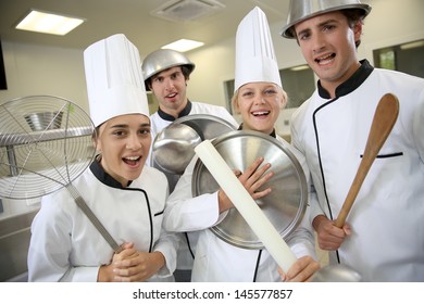 Team Of Young Cooks Being Silly Holding Kitchenware