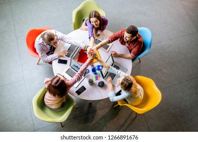 Team Of A Young Coworkers Dressed Casually Working Together With Laptops Sitting At The Round Table In The Office, View From Above