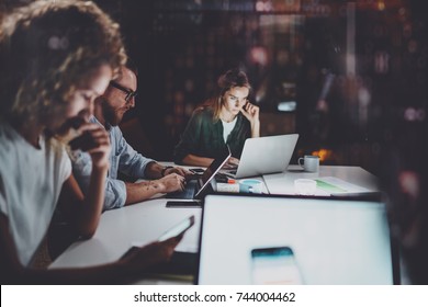 Team Of Young Coworkers Work Together At Night Office.Young People Using Electronic Laptops At The Table.Horizontal.Blurred Background