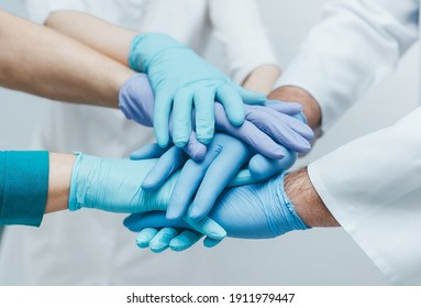 Team of young doctors stacking hands in blue gloves indoor.  medical teamwork. Closeup. Unity concept.