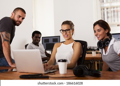 Team Of Young Entrepreneurs Looking At A Laptop Computer In A Tech Startup Office