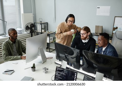 Team of young intercultural office workers in casual clothes looking at data on compute rscreen during work over data decoding - Shutterstock ID 2120006630