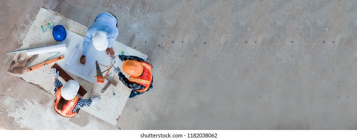 Team of young man and woman engineer and architects working, meeting, discussing,designing, planing, measuring layout of building blueprints in construction site floor at factory.top view & copy space - Shutterstock ID 1182038062