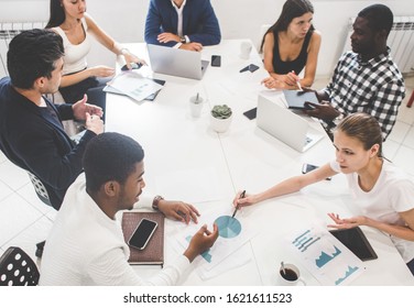A team of young office workers, businessmen with laptop working at the table, communicating together in an office. Corporate businessteam and manager in a meeting. coworking. - Shutterstock ID 1621611523