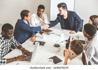 A team of young office workers, businessmen with laptop working at the table, communicating together in an office. Corporate businessteam and manager in a meeting. coworking. - Shutterstock ID 1640478193