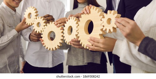 Team of young people making gear chain as metaphor for collaboration, coordinated group work, teamwork, professional interaction, building strong company and effective well-functioning business system - Shutterstock ID 1869308242