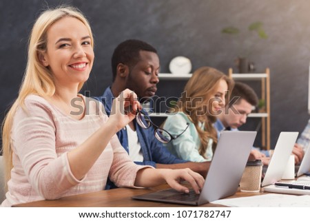 Team of young programmers working in software developing company, typing on laptops, testing new games or apps, copy space