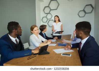 team of young successful people in suits discussing work at the table in the office - Shutterstock ID 1232558206