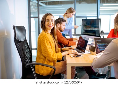 Team Of A Young Woman As A Programmer Sitting In The Office With People Working On The Background