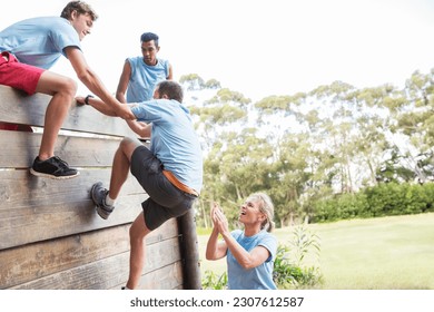 Teammates helping man over wall on boot camp obstacle course - Powered by Shutterstock