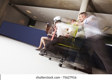 Teams Competing Seriously In An Office Chair Race, Blue Copy Space Area.