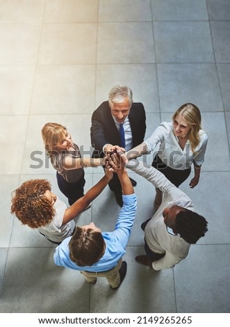 Teamwork always wins. High angle shot of a group of colleagues giving each other a high five in solidarity.