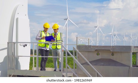 Teamwork of Asian windmill engineer group, worker working on site at wind turbines field or farm, renewable clean energy source. Eco technology for electric power. industry nature environment. People
