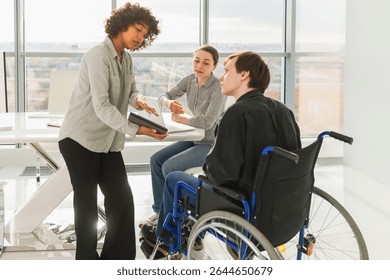 Teamwork brainstorm. Diverse multiracial colleagues man in chair for people with disability working together. Group of people sitting in creative office discussing business. Young professional team