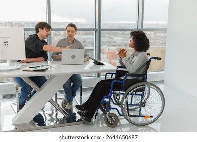 Teamwork brainstorm. Diverse multiracial colleagues woman in chair for people with disability working together. Group of people sitting in creative office discussing business. Young professional team
