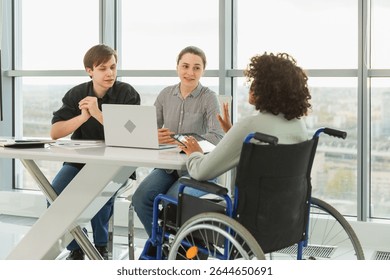 Teamwork brainstorm. Diverse multiracial colleagues woman in chair for people with disability working together. Group of people sitting in creative office discussing business. Young professional team