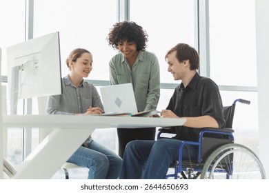 Teamwork brainstorm. Diverse multiracial colleagues man in chair for people with disability working together. Group of people sitting in creative office discussing business. Young professional team