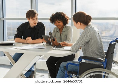 Teamwork brainstorm. Diverse multiracial colleagues woman in chair for people with disability working together. Group of people sitting in creative office discussing business. Young professional team