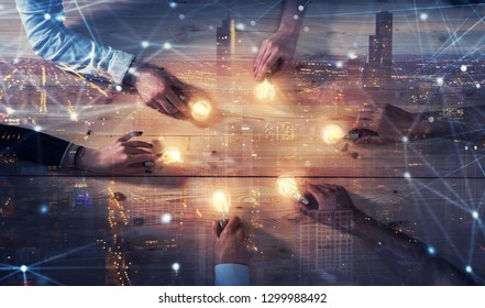 Teamwork and brainstorming concept with businessmen that share an idea with a lamp. Concept of startup. Double exposure - Shutterstock ID 1299988492
