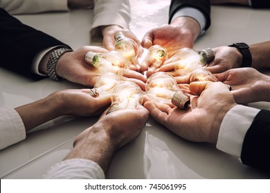 Teamwork and brainstorming concept with businessmen that share an idea with a lamp. Concept of startup - Shutterstock ID 745061995