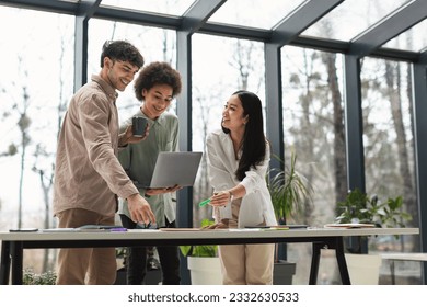 Teamwork. Business Team At Office Interior Working With Laptop And Papers Standing Around Table Together. Three Arabic, African And Asian Colleagues Websurfing Enjoying Professional Cooperation - Powered by Shutterstock