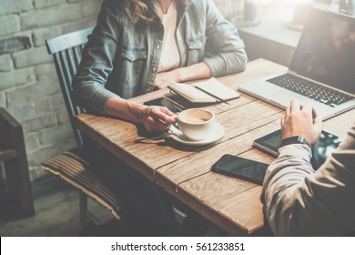 Teamwork. Businessman and businesswoman sitting at table in coffee shop and discuss business plan. On table is laptop, tablet, smartphone, notebook, cup of coffee.Business meeting of partners in cafe. - Powered by Shutterstock