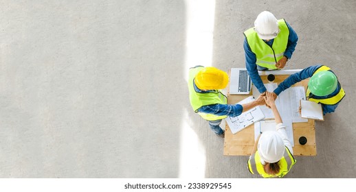 Teamwork of civil technician engineer and professional architect stacked hand working together while discuss the planning of building construction progress at site top view banner copy space - Powered by Shutterstock