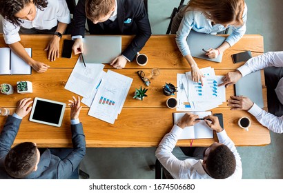 Teamwork Concept. Mixed Business Team Working Together Sitting At One Table In Modern Office. Above View